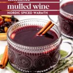 Two glass mugs of Danish mulled wine with cinnamon sticks, placed on a green cloth next to dried fruits and cinnamon sticks. Text overlay reads "danish mulled wine – nordic spiced warmth.