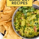 A bowl of guacamole garnished with cilantro is served with tortilla chips on a black plate. Text reads: "15 Game Day Recipes.