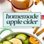 Photo of a mug of apple cider with a cinnamon stick and apple slice garnish, and a pot filled with sliced apples, oranges, spices, and water for making homemade apple cider.