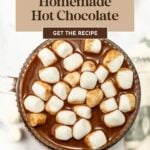 A mug of hot chocolate topped with mini marshmallows, viewed from above, with text promoting a homemade hot chocolate recipe.