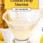 A lemon drop martini in a glass with a sugared rim, surrounded by fresh lemons and a jigger, with a recipe label above.