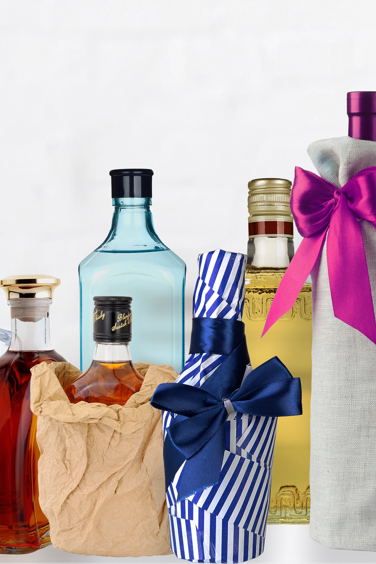 Five assorted liquor bottles, some wrapped in paper or fabric and some with bows, are arranged in a row against a plain white background.