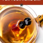 A glass of brandy garnished with two black cherries on a cocktail pick, viewed from above, with text that reads “the best brandy for your home bar.”.