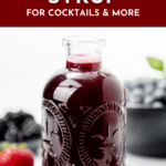 A glass bottle of Mixed Berry Syrup with fresh berries nearby and text promoting a delicious recipe for cocktails and more.