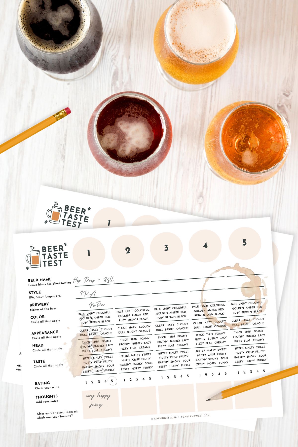 Four glasses of beer and two beer tasting sheets with pencil and spilled beer on a white wooden table.
