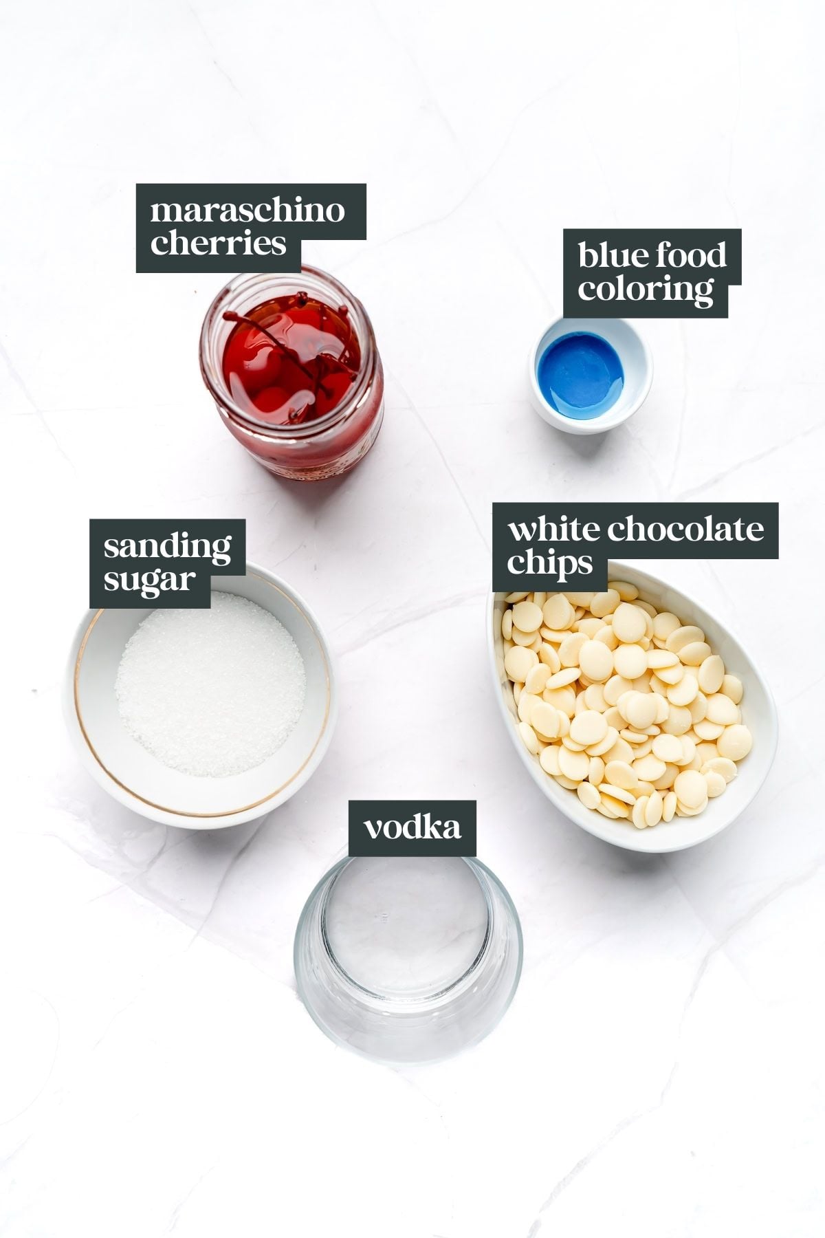 Top-down view of cherry bombs made with maraschino cherries, blue food coloring, sanding sugar, white chocolate chips, and vodka.