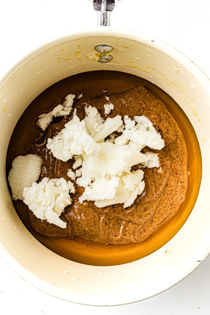 A saucepan with almond butter, solid coconut oil, and honey before mixing.