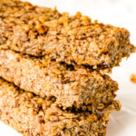 Three stacked homemade granola bars with visible oats and nuts on a white background.