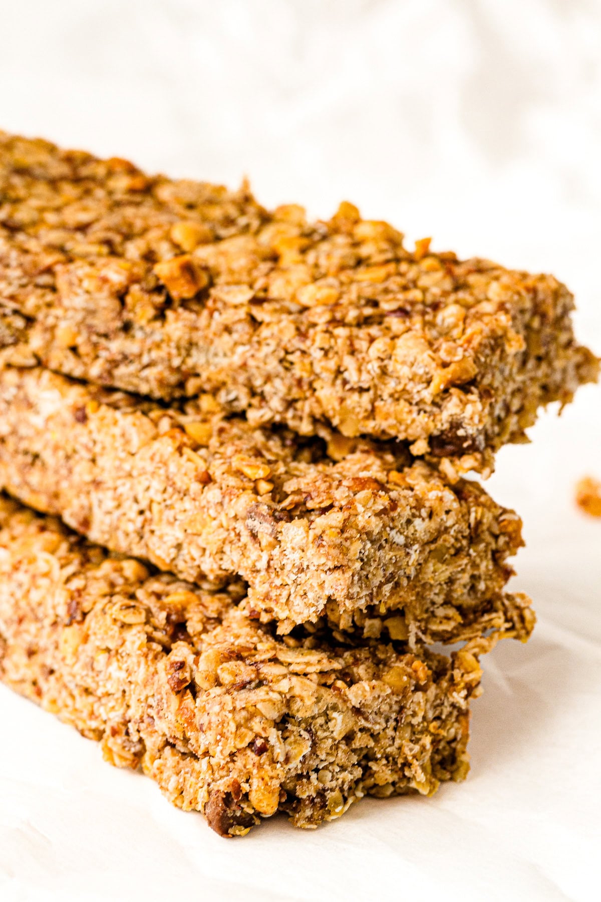Three stacked homemade granola bars with visible oats and nuts on a white background.