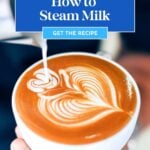 A hand holds a cup of latte with heart-shaped latte art as steamed milk is poured in; text reads "How to Steam Milk.