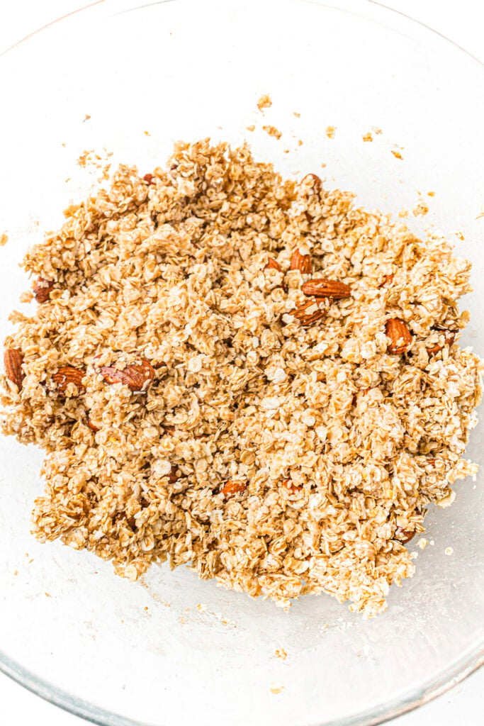 A glass bowl filled with a mixture of oats and nuts, ready for baking or cooking.