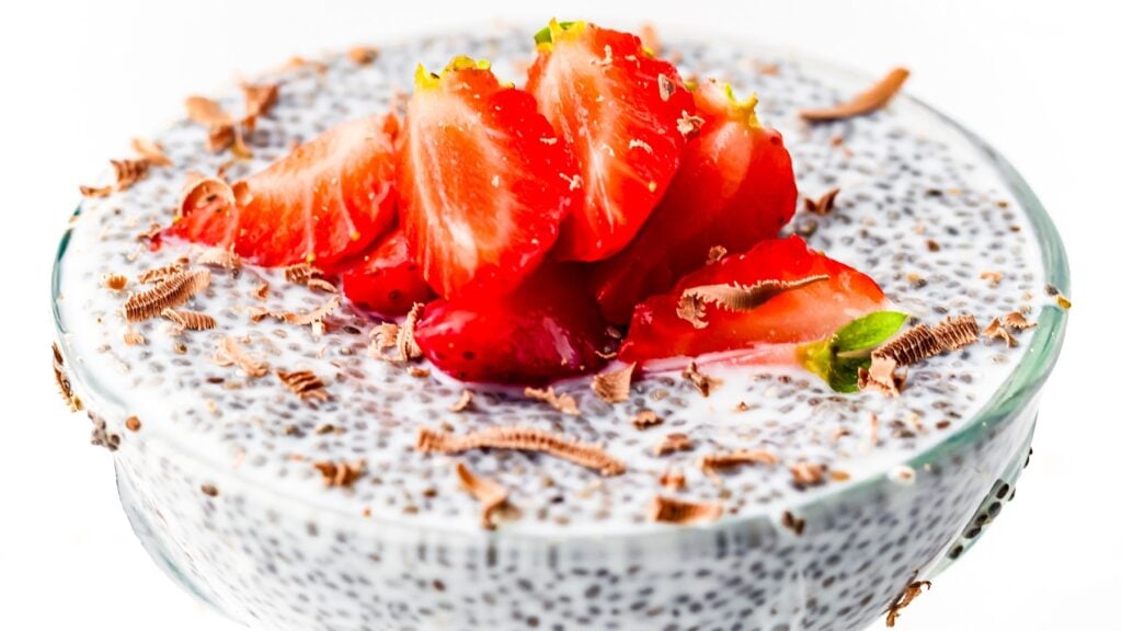 Chia pudding topped with sliced strawberries and chocolate shavings in a glass bowl.
