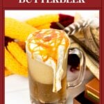 A glass of frozen butterbeer topped with whipped cream and caramel, with fall decor and a golden spoon nearby.
