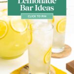 Two glasses of lemonade with ice and lemon slices, next to a pitcher on yellow napkins.