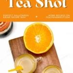 Two orange tea shots on a wooden board, garnished with orange slices, next to a halved orange.