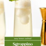 A tall glass of Sgroppino Prosecco Float with a lemon garnish and mint, next to a gold spoon.