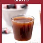 A brown Tootsie Roll shot in a clear glass, with Tootsie Roll candies in the background.