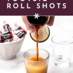 A hand pours a brown shot into a glass; Tootsie Rolls and an empty glass sit nearby.