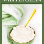 A green bowl of whipped cream with a yellow spoon, next to a green and white towel.