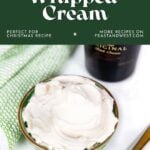 A bowl of whipped cream next to a gold spoon, green towel, and a Baileys bottle on a white surface.
