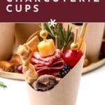 A paper cup filled with meat, cheese, olives, berries, and herbs, labeled “Homemade Charcuterie Cups.”.