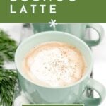 Green mug of eggnog latte with whipped cream, surrounded by pine, with text about making eggnog lattes.