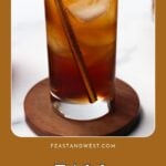 Iced coffee with a straw in a tall glass on a wooden coaster, text reads “Fall Coffee Drinks.”.