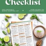 A home bar checklist sits on a table with limes, ice, mint, and bar tools arranged around it.