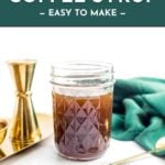 A mason jar of Irish cream coffee syrup sits beside gold bar tools and a green cloth on a white surface.
