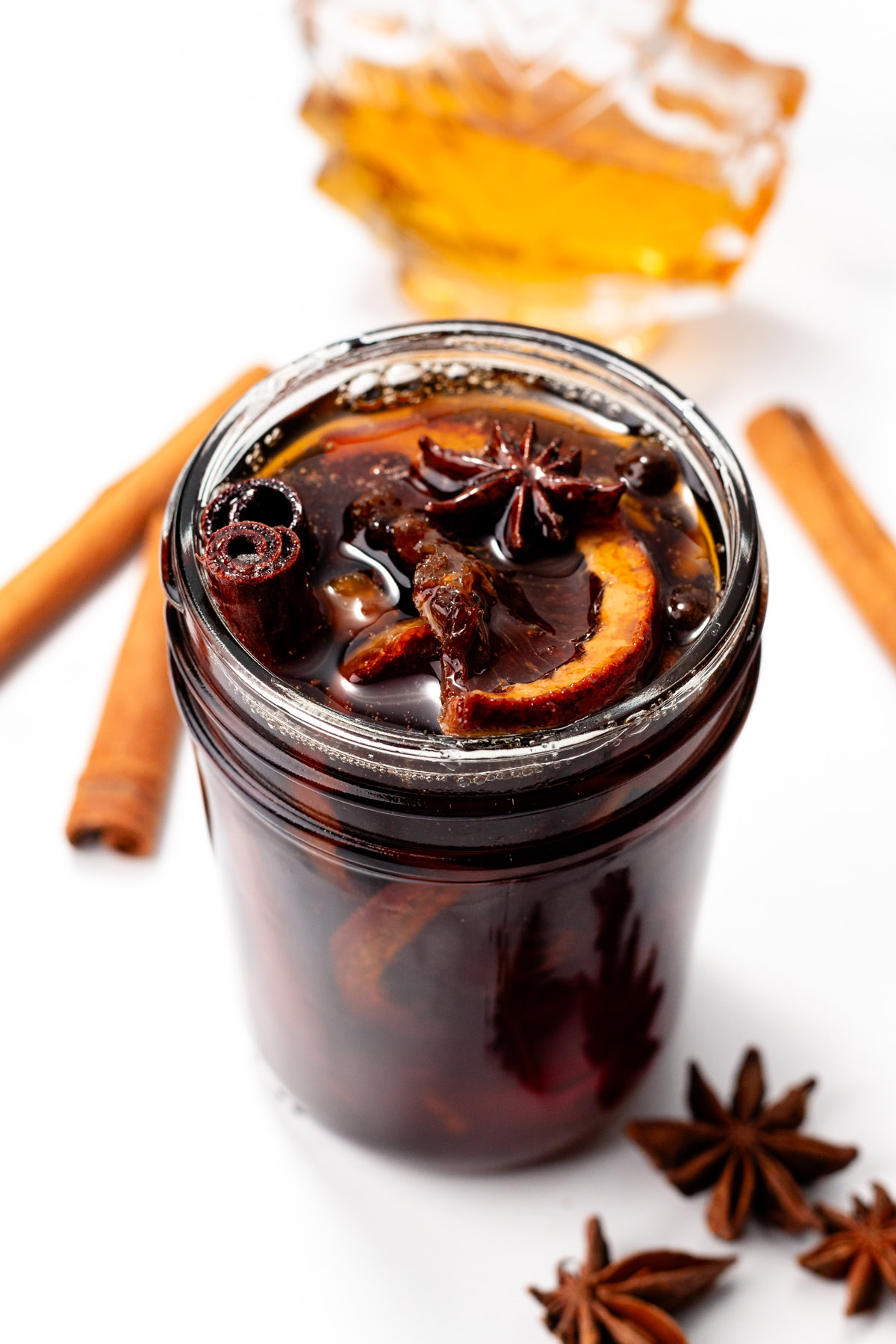 A jar of homemade spiced syrup with orange slices, cinnamon sticks, and star anise.