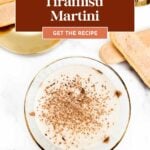 Overhead view of a tiramisu martini in a glass, with ladyfinger cookies on plates beside it.