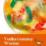 A bowl of colorful gummy worms in bubbly liquid, labeled as vodka gummy worms for Halloween parties.