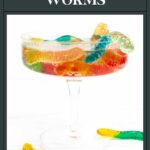 A glass filled with colorful gummy worms soaked in liquid, labeled “Vodka Gummy Worms.”.