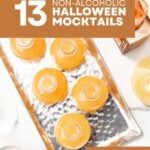 Five glass bottles filled with orange liquid on a silver tray, with text reading: 13 Non-Alcoholic Halloween Mocktails.
