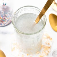 Glass of clear, shimmery liquid with a gold spoon.