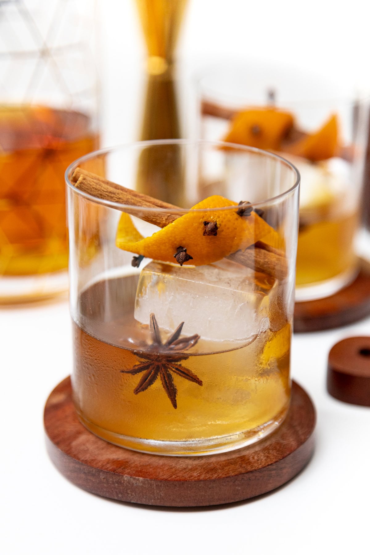 An old fashioned cocktail garnished with an orange twist, cloves, a cinnamon stick, and a star anise.
