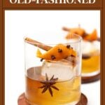 Spiced Old-Fashioned cocktail in a glass with a large ice cube, star anise, cinnamon stick, and orange peel.