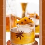 Spiced Old Fashioned cocktail garnished with a cinnamon stick, orange peel, cloves, and a star anise.